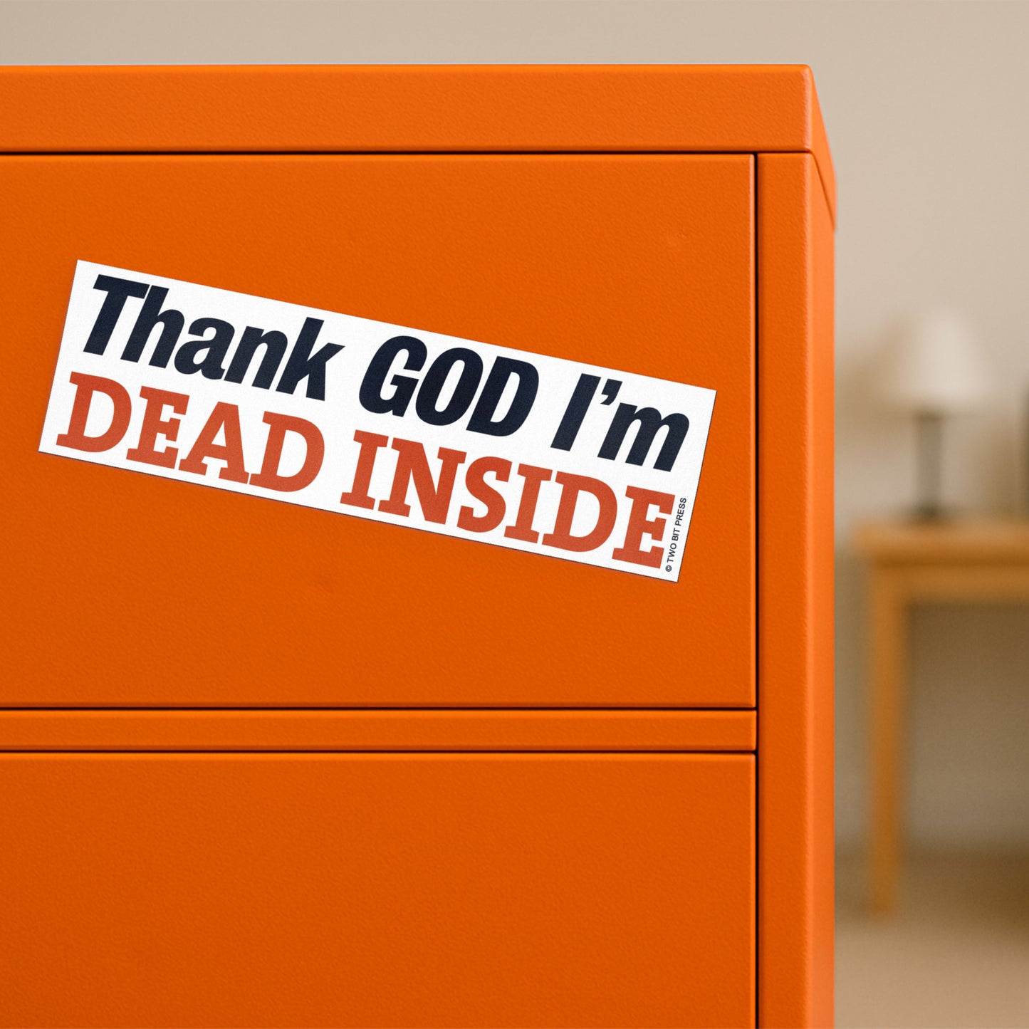 A vinyl bumper magnet reading "Thank GOD I'm DEAD INSIDE" on orange filing cabinet.