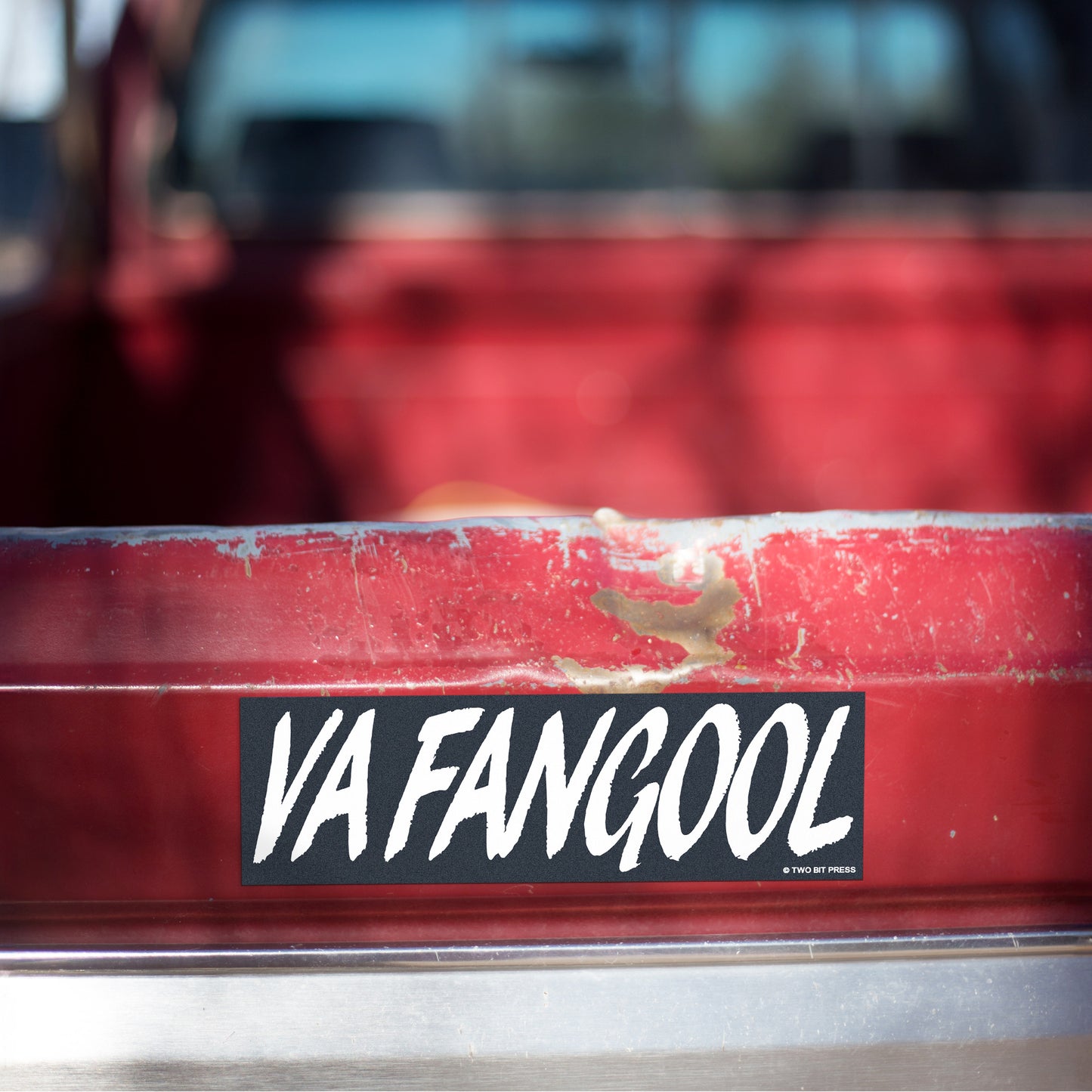 A vinyl bumper magnet reading "VAFANGOOL" on red truck tailgate.