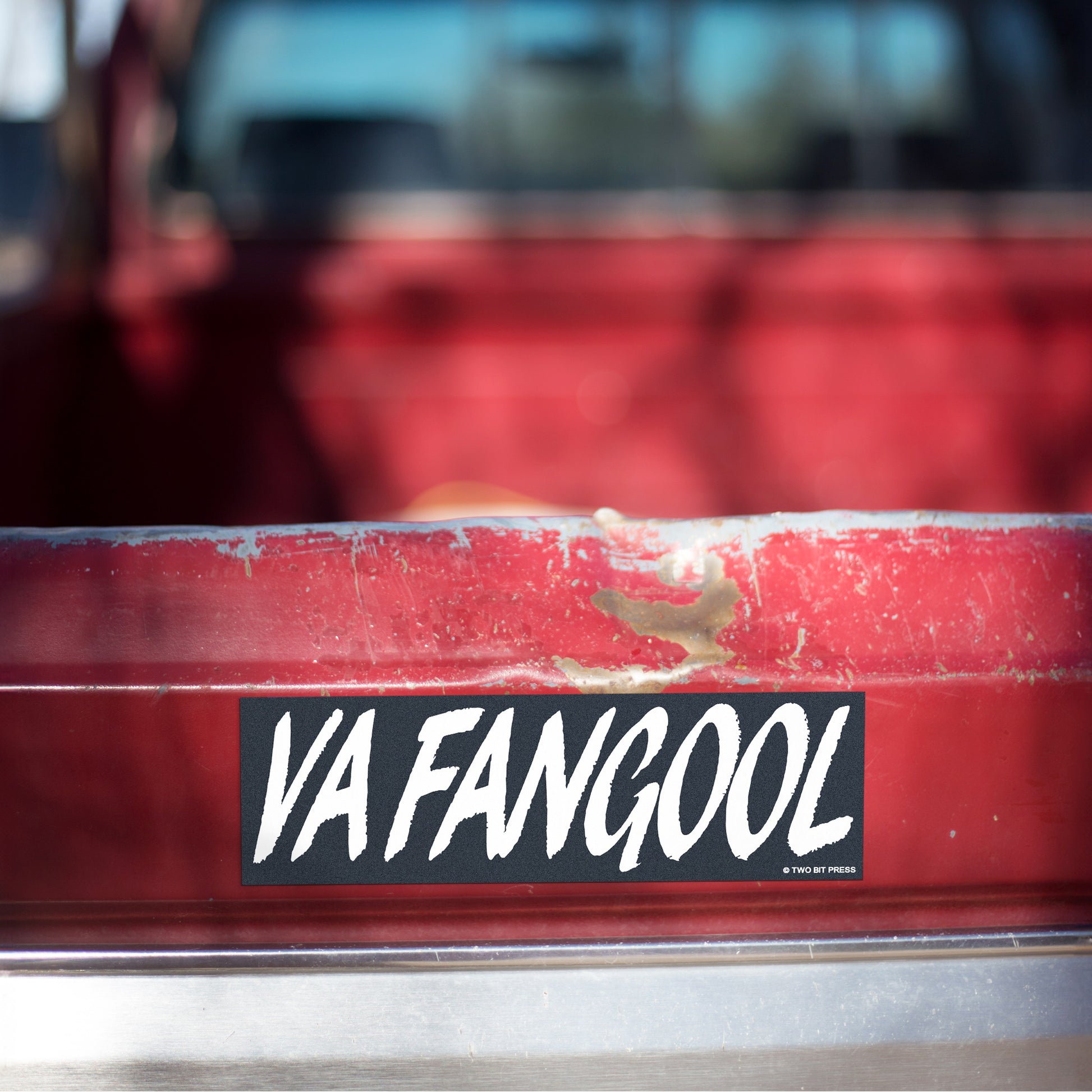 A vinyl bumper magnet reading "VAFANGOOL" on red truck tailgate.