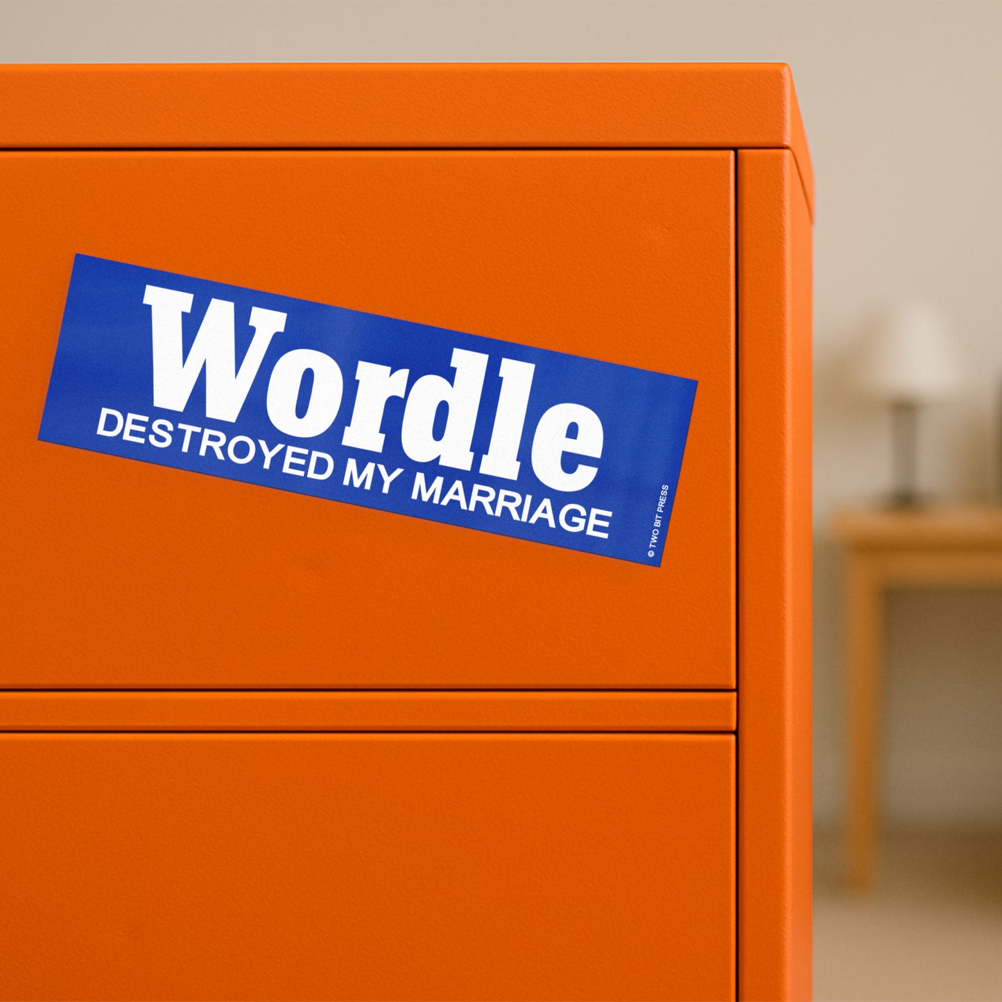 A vinyl bumper magnet reading "WORDLE DESTROYED MY MARRIAGE" on orange filing cabinet.