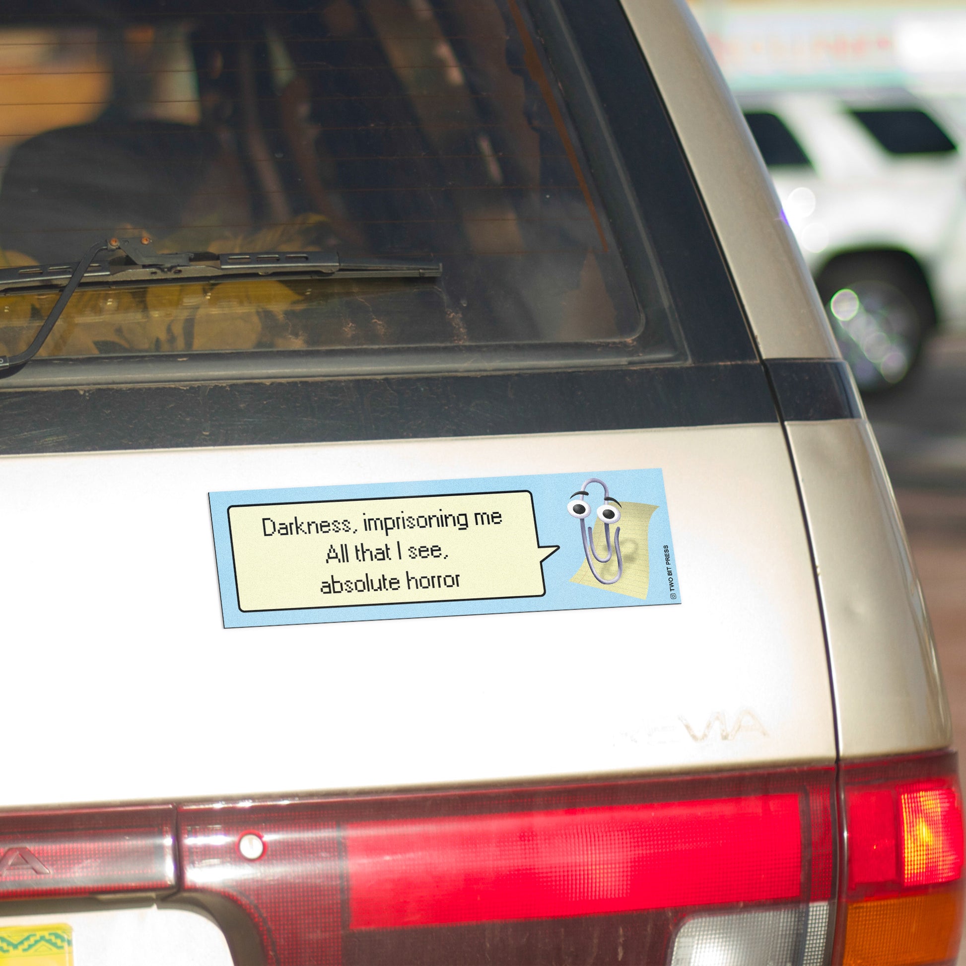 A bumper magnet showing Clippy and the text "Darkness imprisoning me All that I see absolute horror" on gold minivan.