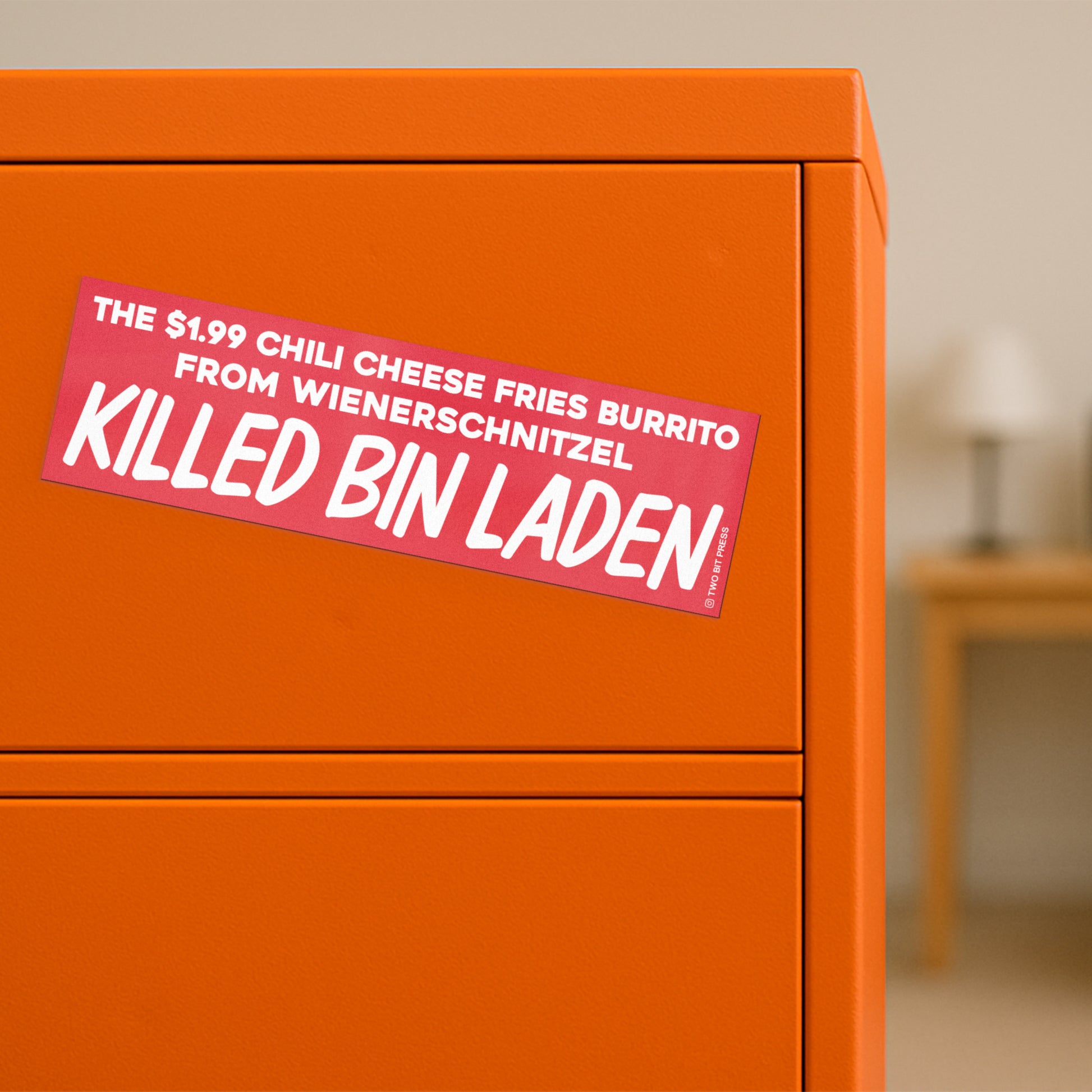 A bumper magnet reading "THE $1.99 CHILI CHEESE FRIES BURRITO FROM WIENERSCHNITZEL KILLED BIN LADEN" on orange filing cabinet.