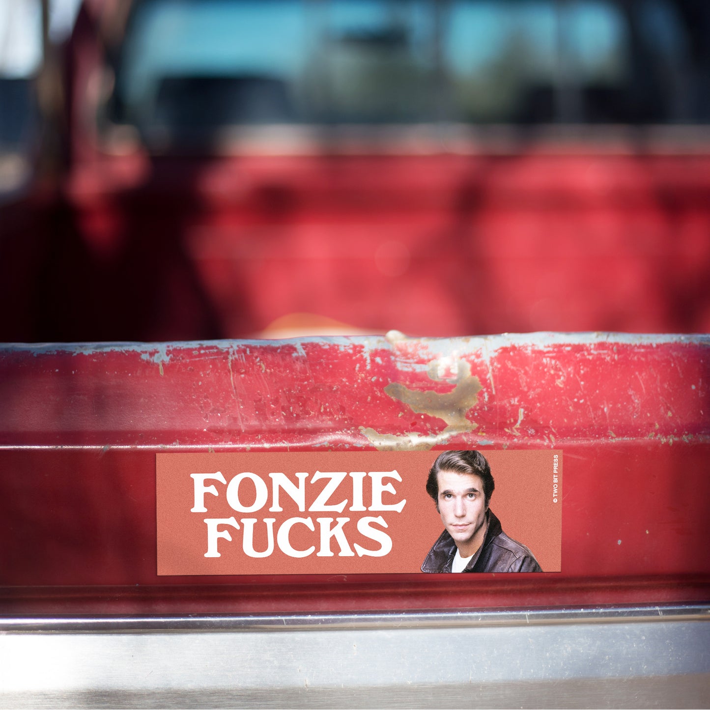 A vinyl bumper magnet showing the Fonz and the text "FONZIE FUCKS" on red truck tailgate.