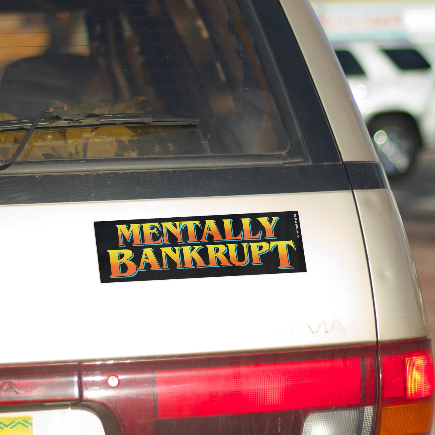 A vinyl bumper magnet reading "MENTALLY BANKRUPT" on gold minivan.