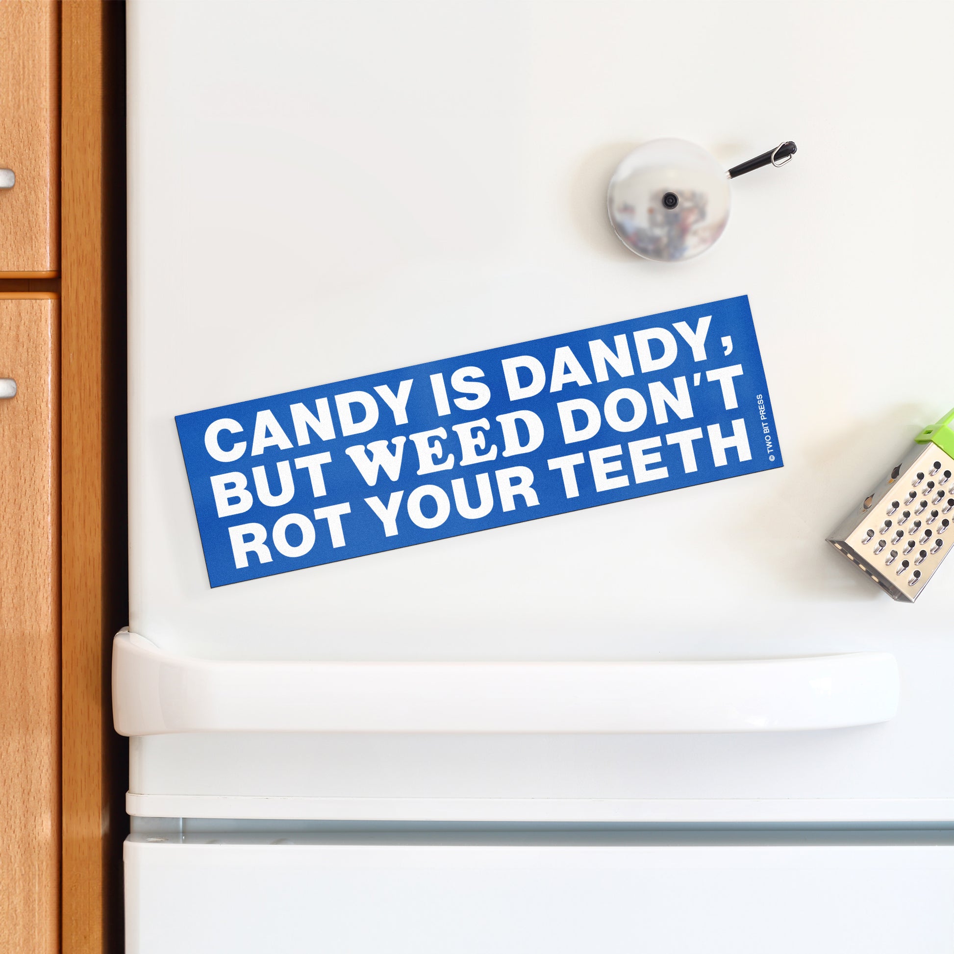 A vinyl bumper magnet reading "CANDY IS DANDY, BUT WEED DON'T ROT YOUR TEETH" on a white fridge.
