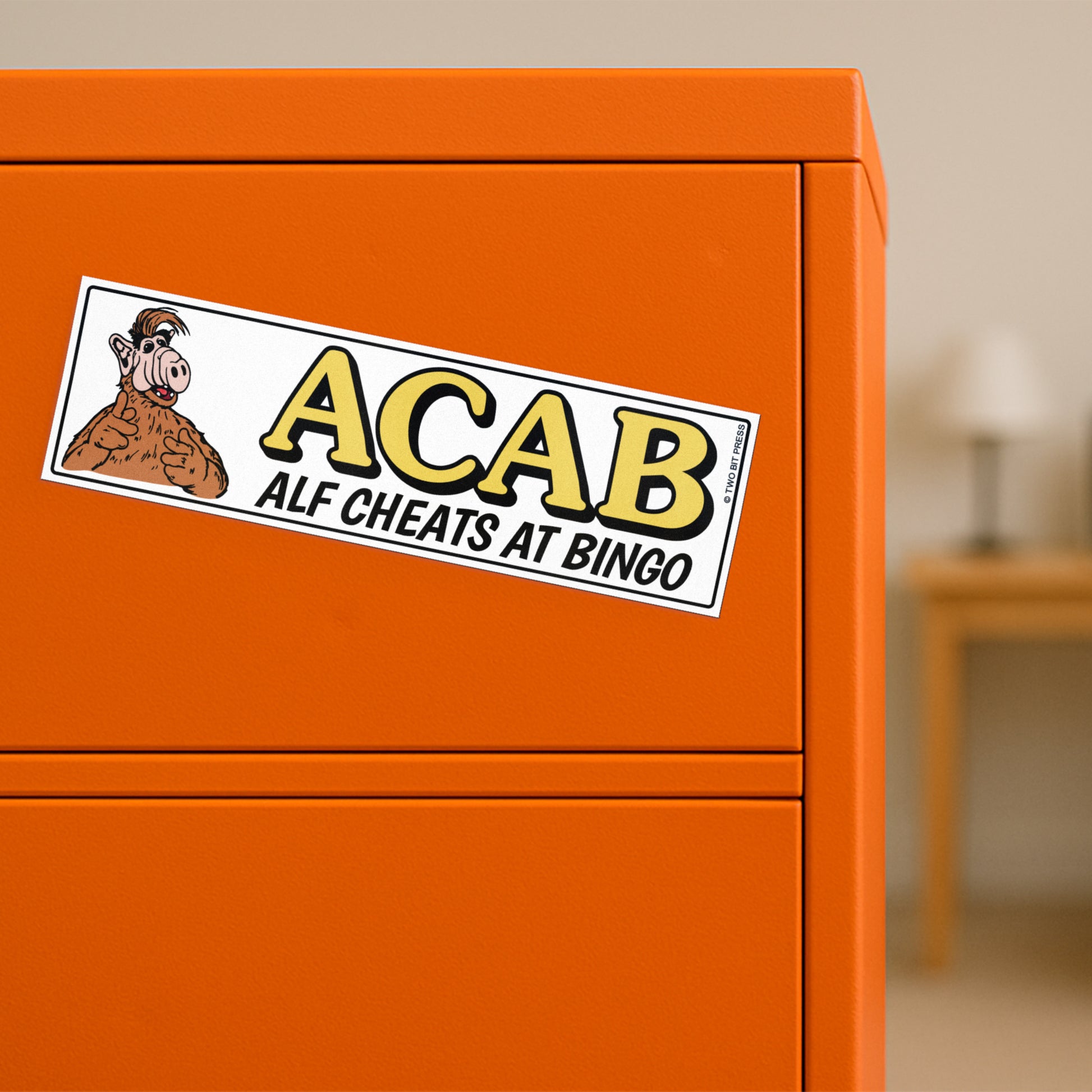 A vinyl bumper magnet showing Alf and the text "ACAB Alf Cheats at Bingo" on orange filing cabinet.