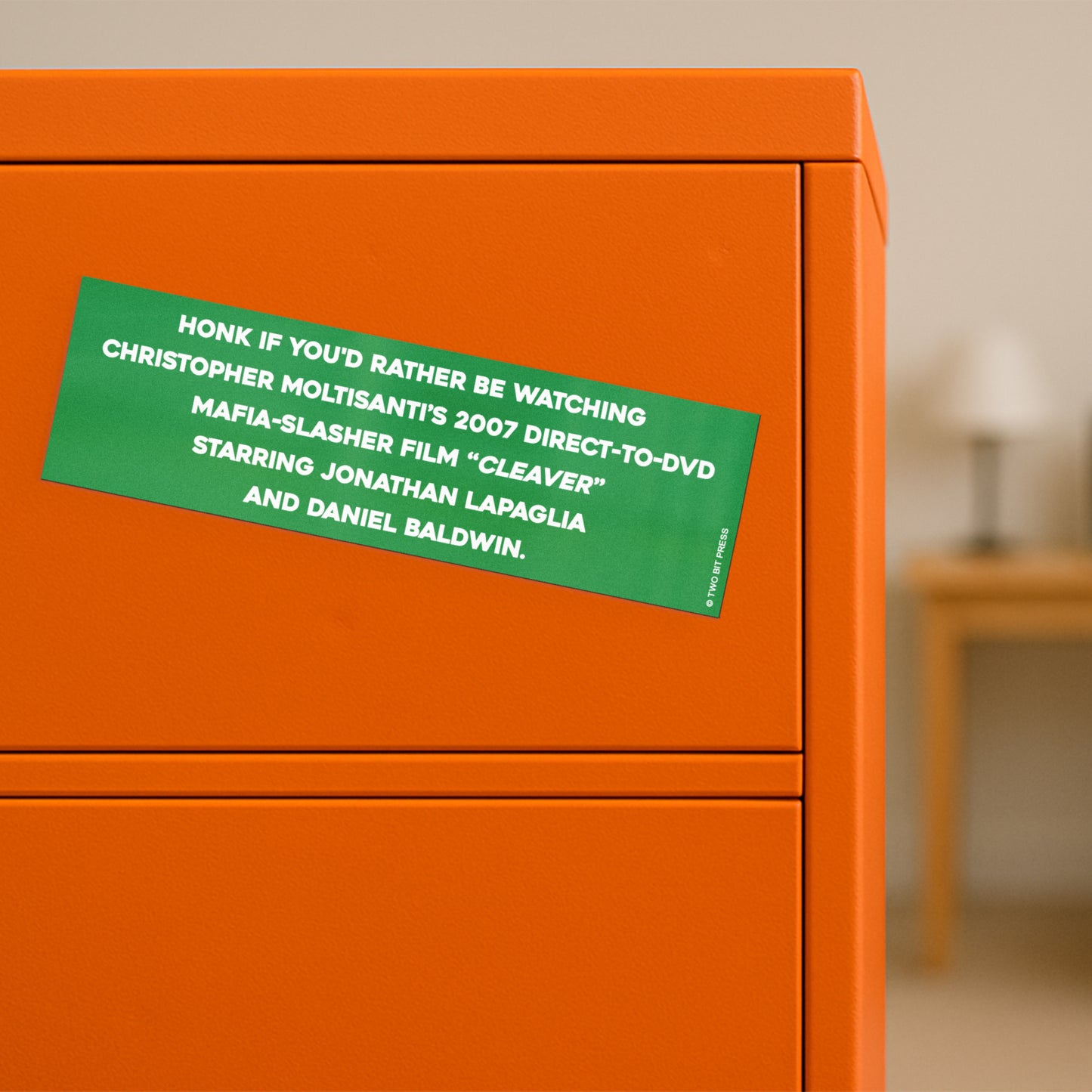 A vinyl bumper magnet reading "HONK IF YOU'D RATHER BE WATCHING CLEAVER" on orange filing cabinet.