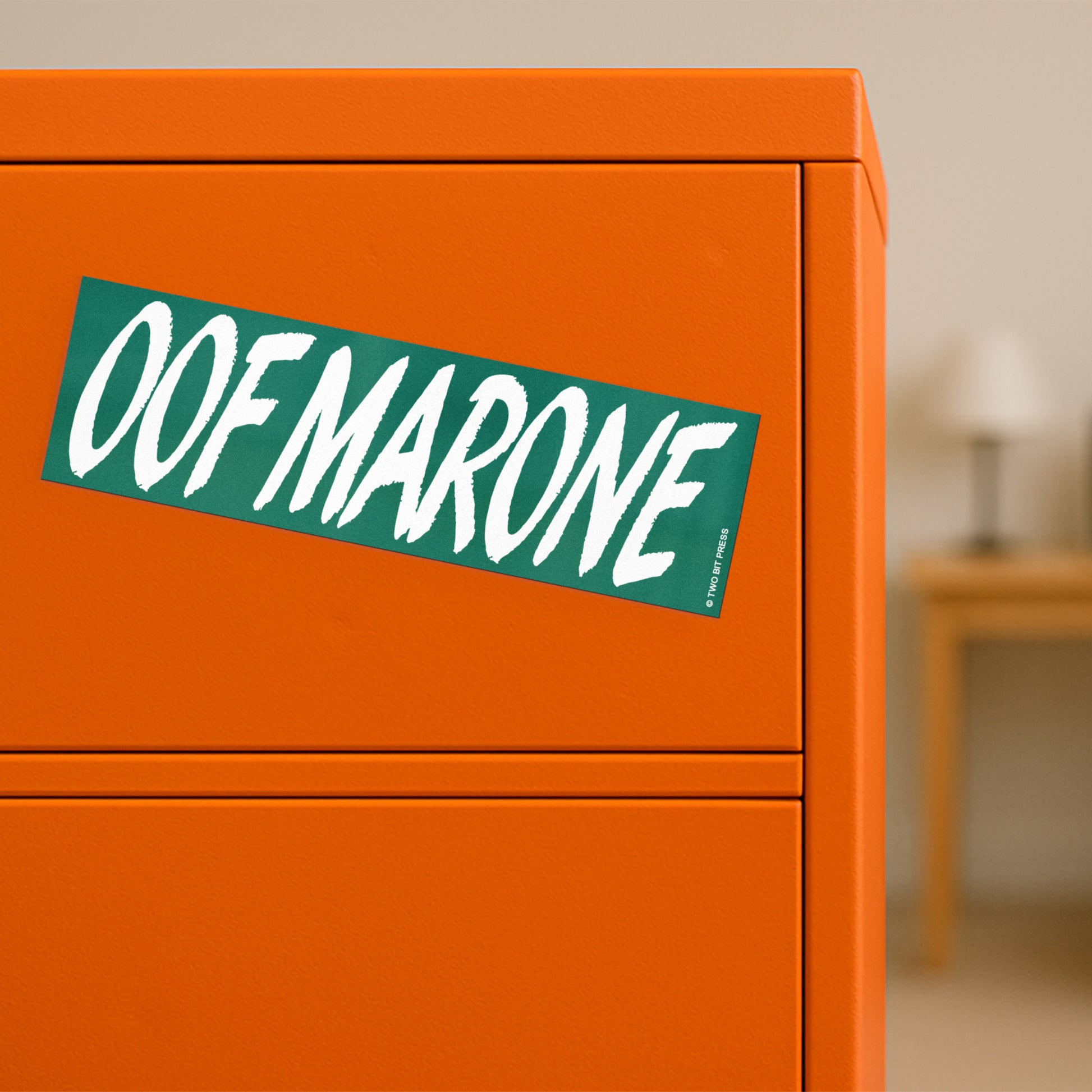 A vinyl bumper magnet reading "OOF MARONE" on orange filing cabinet.