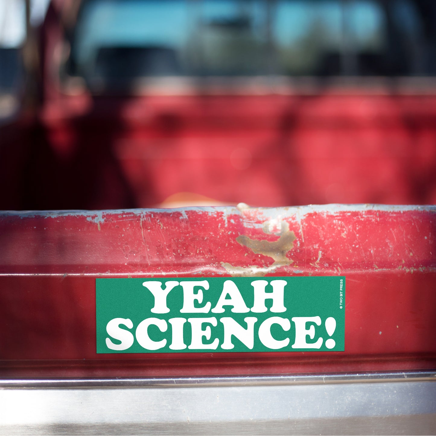 A vinyl bumper magnet reading "YEAH SCIENCE!" on red truck tailgate.