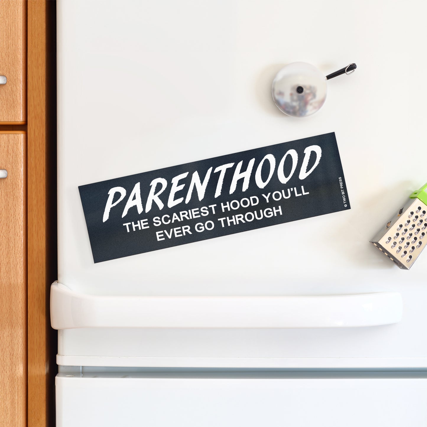 A vinyl bumper magnet reading "PARENTHOOD THE SCARIEST HOOD YOU'LL EVER GO THROUGH" on a white fridge.