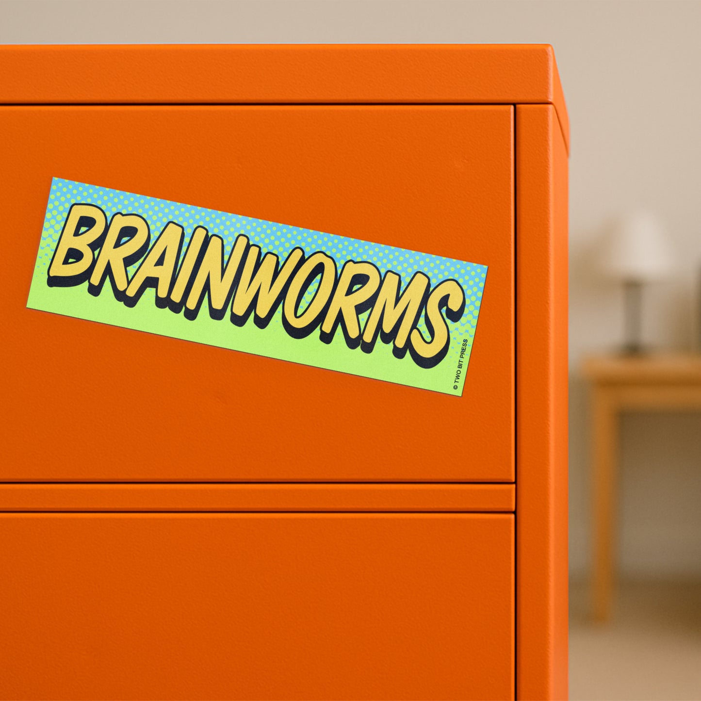A vinyl bumper magnet reading "BRAINWORMS" on orange filing cabinet.