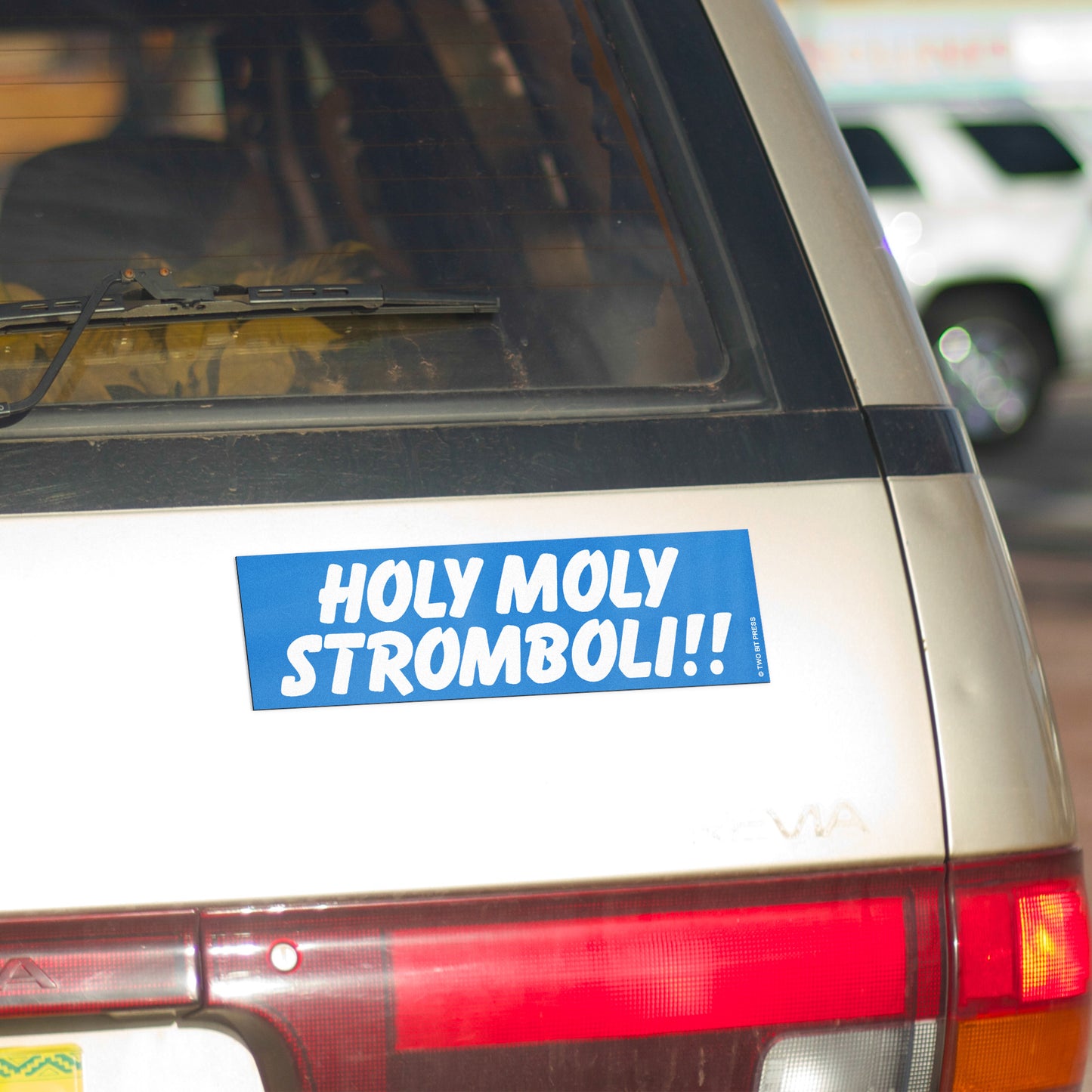 A vinyl bumper magnet reading "HOLY MOLY STROMBOLI!!" on gold minivan.