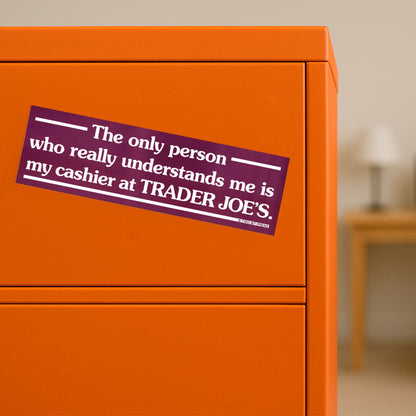 A vinyl bumper magnet reading "The only person who understands me is my cashier at TRADER JOE'S." on orange filing cabinet.