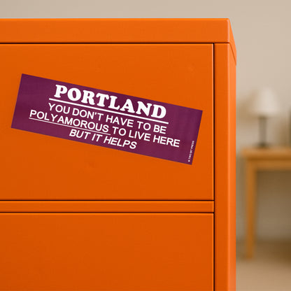 A vinyl bumper magnet reading "PORTLAND YOU DON'T HAVE TO BE POLYAMOROUSTO LIVE HERE BUT IT HELPS" on orange filing cabinet.