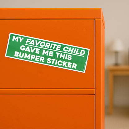 A vinyl bumper magnet reading "MY FAVORITE CHILD GAVE ME THIS bumper magnet" on orange filing cabinet.