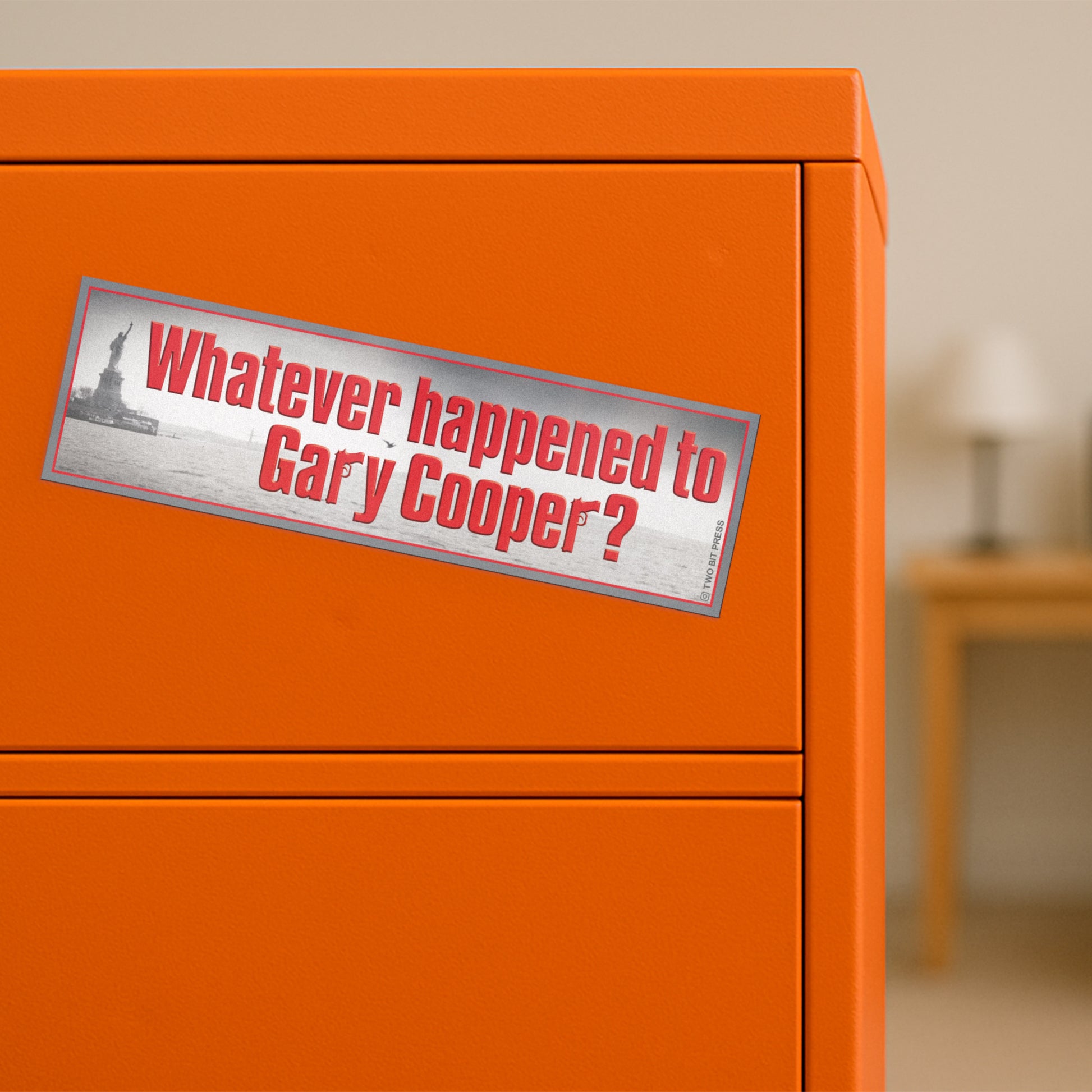 A vinyl bumper magnet reading "Whatever Happened to Gary Cooper?" on orange filing cabinet.