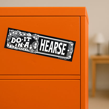 A vinyl bumper magnet reading "DO IT IN A HEARSE" on orange filing cabinet.