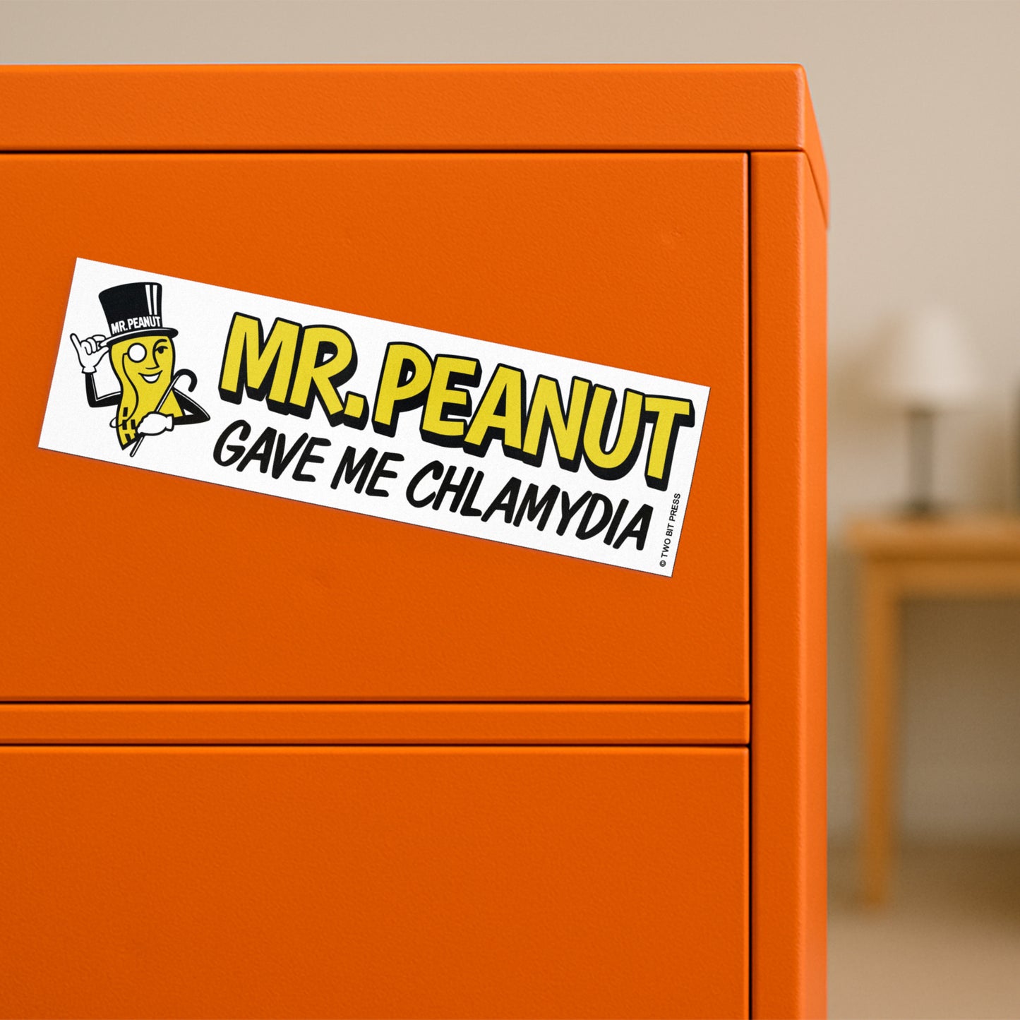 A vinyl bumper magnet shwoing Mr. Peanut and the text "MR. PEANUT GAVE ME CHLAMYDIA" on orange filing cabinet.