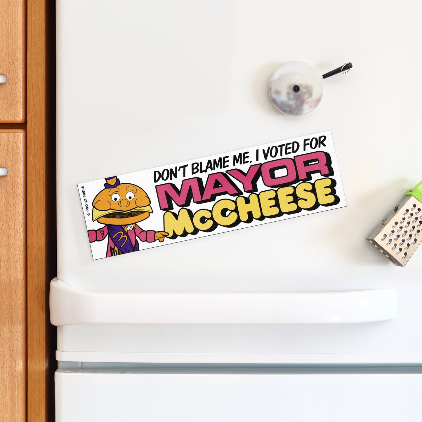 A vinyl bumper magnet showing Mayor McCheese and the text "DON‚àö√ØT BLAME ME I VOTED FOR MAYOR MCCHEESE" on a white fridge.