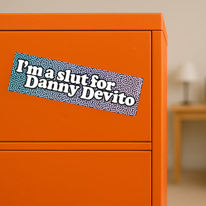 A vinyl bumper magnet reading "I'm a slut for Danny Devito" on orange filing cabinet.