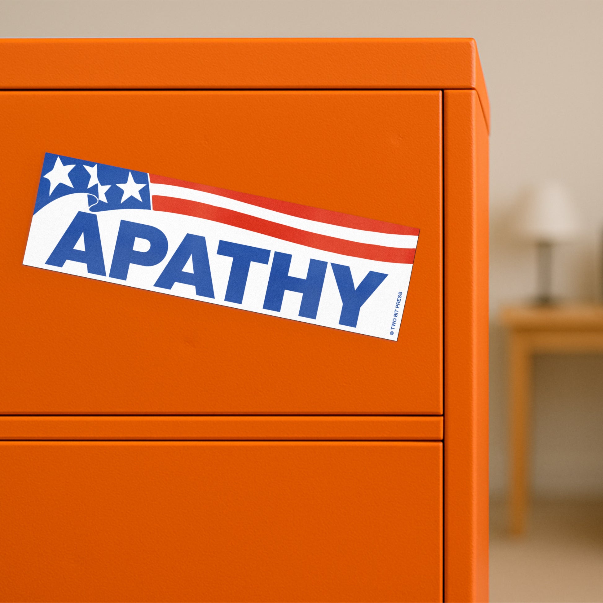 A vinyl bumper magnet showing the American flag and the text "APATHY" on orange filing cabinet.